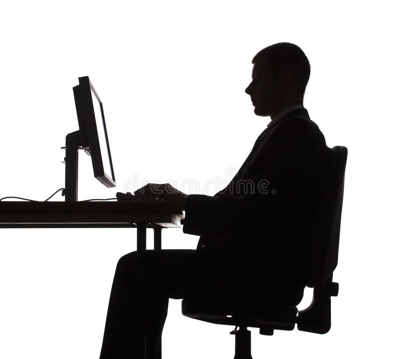 Silhouet van een man die aan een computer werkt stock foto
