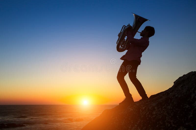 Silhouet van musicus die de trompet op rotsachtige overzeese kust spelen tijdens zonsondergang royalty-vrije stock afbeelding Silhouet van musicus die de trompet op rotsachtige overzeese kust spelen tijdens zonsondergang royalty-vrije stock afbeelding