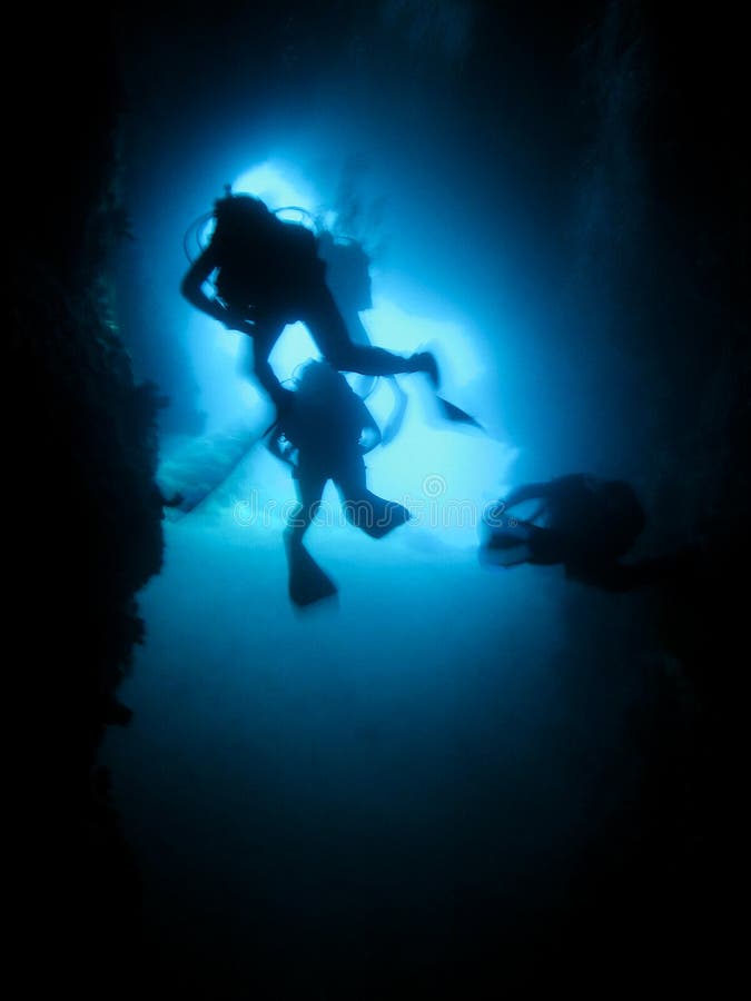 Silhouet van scuba-duikers in een onderwaterhol royalty-vrije stock fotografie Silhouet van scuba-duikers in een onderwaterhol royalty-vrije stock fotografie