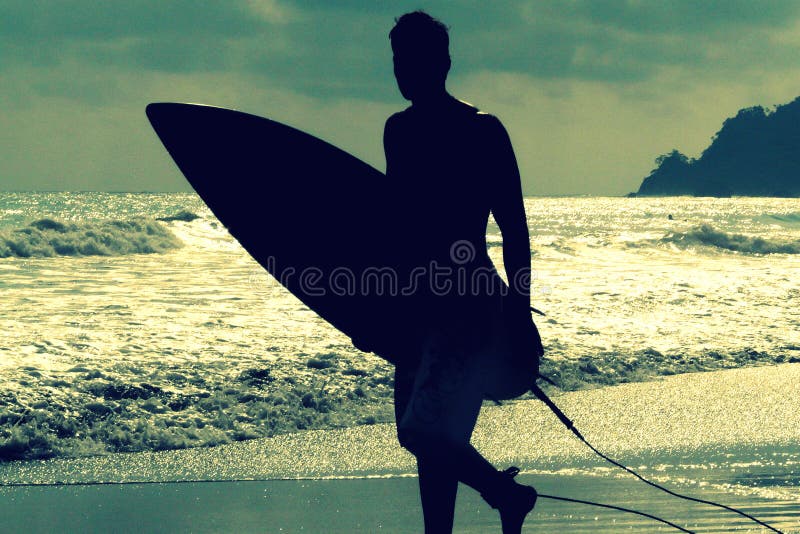 Silhouet van surfer met een raad op een zonsondergangavond in het Nationale Park Costa Rica van Manuel Antonio royalty-vrije stock fotografie Silhouet van surfer met een raad op een zonsondergangavond in het Nationale Park Costa Rica van Manuel Antonio royalty-vrije stock fotografie