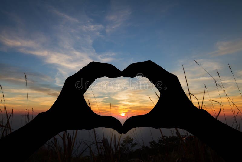 Silhouethart gevormde handen die op vage zonsondergang over berg gesturing stock foto Silhouethart gevormde handen die op vage zonsondergang over berg gesturing stock foto