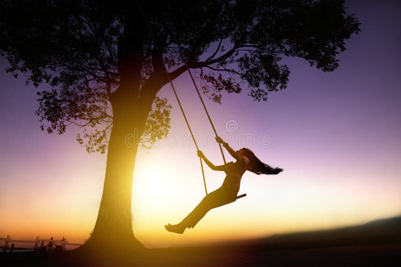 Silhouette of happy young woman on a swing with sunset background. Silhouette of happy young woman on a swing with sunset background