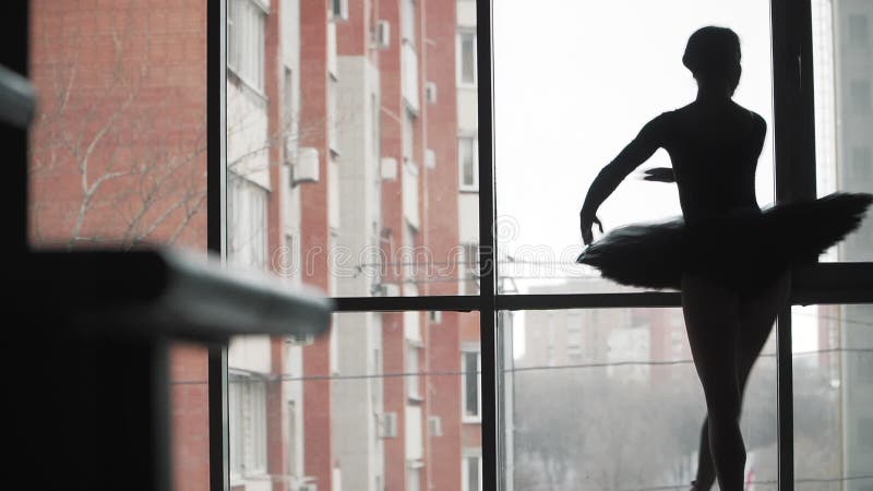 Silhouette Ballerina in un tutu nero balletto sullo sfondo della finestra e della città Movimento lento Un frame statico