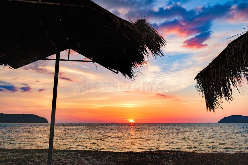 Silhouette of the beach hut and the setting sun