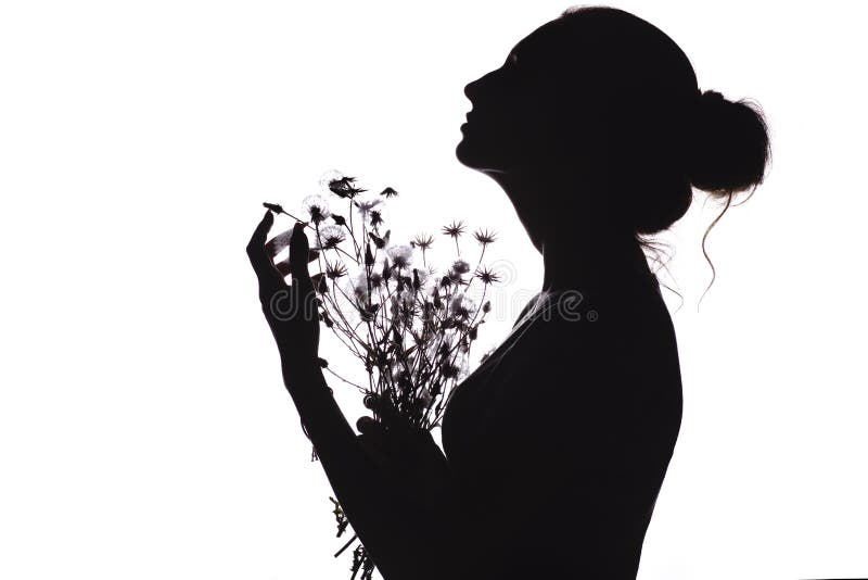 Silhouette of a beautiful girl with a bouquet of dried flowers, face profile of a young woman looking upwards on a white isolated