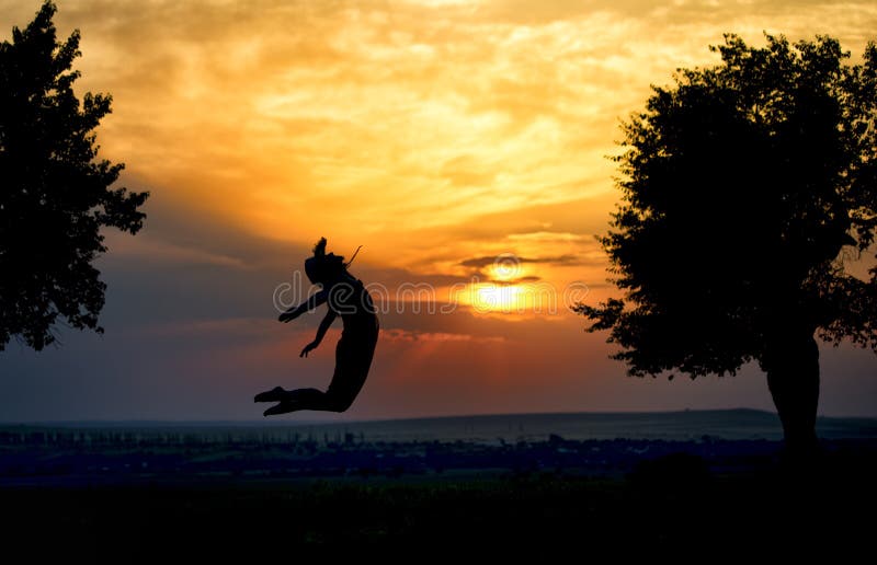 Silhouette of a beautiful girl jumping in the sunset