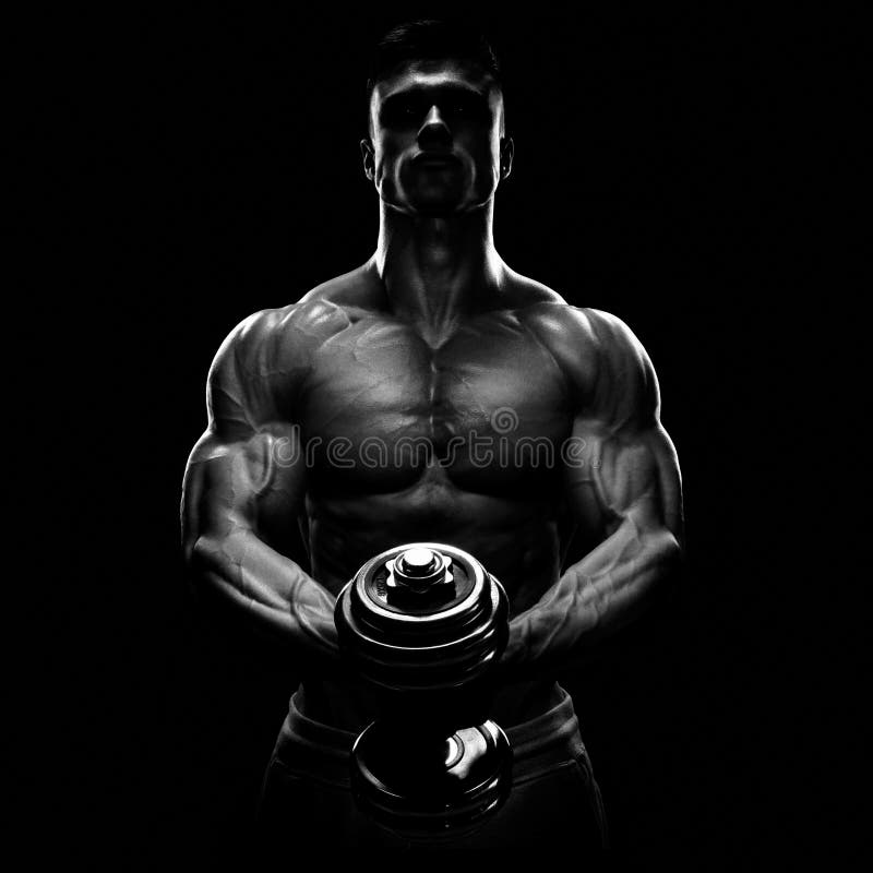 Silhouette of a bodybuilder. Power athletic man pumping up muscles with dumbbell. Confident young fitness man with strong core muscles, power hands and clenched fists. Dramatic light. Silhouette of a bodybuilder. Power athletic man pumping up muscles with dumbbell. Confident young fitness man with strong core muscles, power hands and clenched fists. Dramatic light.