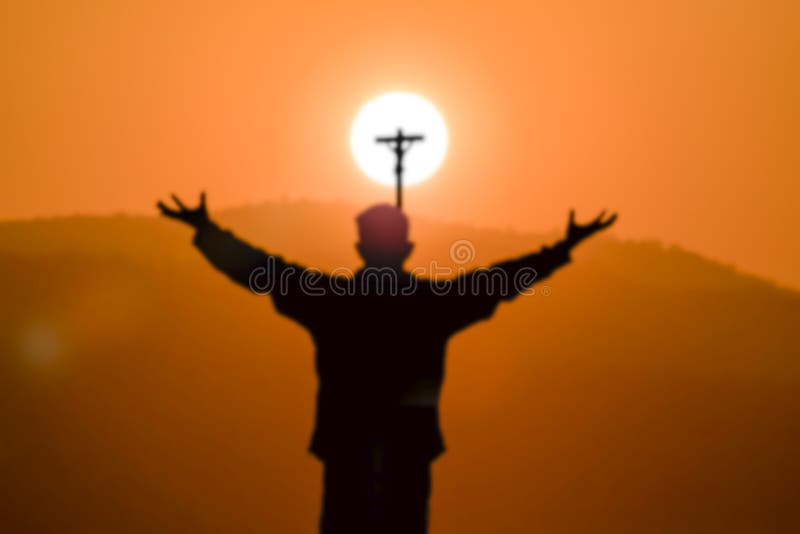 Silhouette brouillée de croix de prière de l'homme à la montagne le temps de coucher du soleil photo stock Silhouette brouillée de croix de prière de l'homme à la montagne le temps de coucher du soleil photo stock