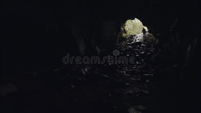Silhouette of a cave explorer in the underground with the entrance behind him, tourism and nature concept. Stock footage royalty free stock image Silhouette of a cave explorer in the underground with the entrance behind him, tourism and nature concept. Stock footage royalty free stock image