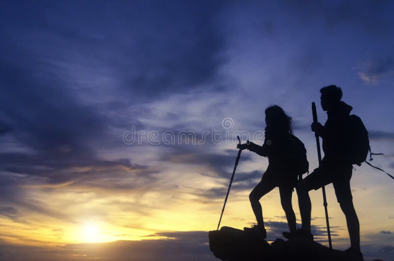 Silhouette of a champion couple on the top of a rock mountain vi