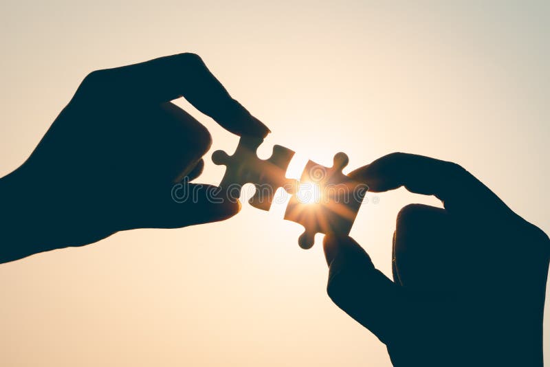 Silhouette of closeup woman and man hand connecting a piece of jigsaw puzzle over sunlight effect. symbol of association and stock photos Silhouette of closeup woman and man hand connecting a piece of jigsaw puzzle over sunlight effect. symbol of association and stock photos