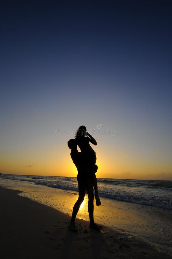 Silhouette of couple on beach at sunset