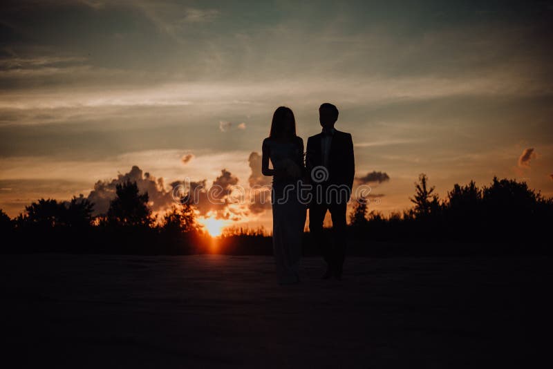 silhouette couple of guy kiss girl on sand in classic dress. trees and sky on background royalty free stock image silhouette couple of guy kiss girl on sand in classic dress. trees and sky on background royalty free stock image
