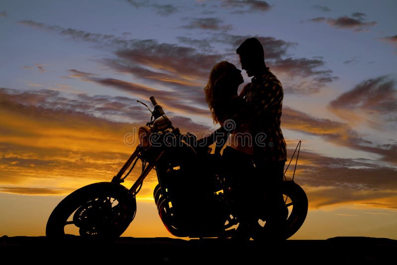 Silhouette couple kiss on motorcycle