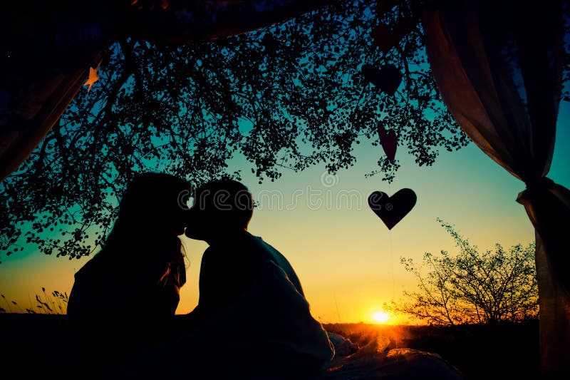 Silhouette of couple in love kissing at sunset