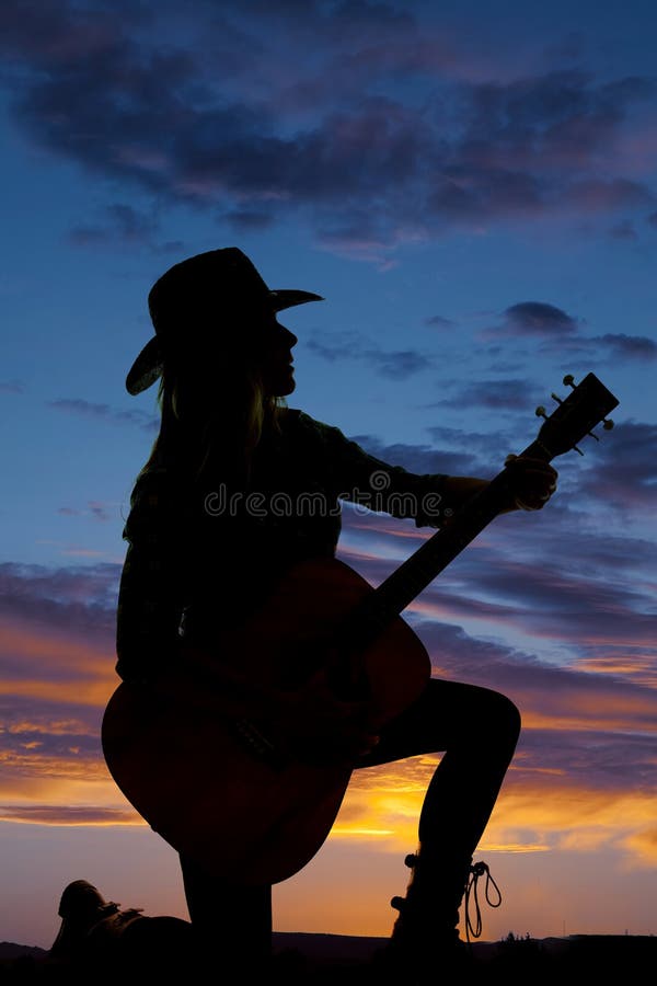 Silhouette cowgirl kneel with guitar look side