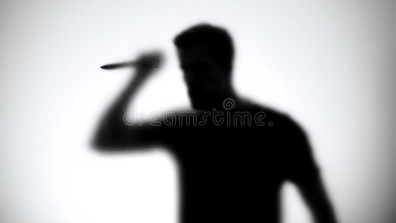 Silhouette of crazy maniac with knife standing behind glass wall, thriller royalty free stock photo Silhouette of crazy maniac with knife standing behind glass wall, thriller royalty free stock photo