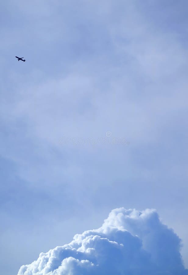 Silhouette d'un avion de vol sur le ciel nuageux bleu lumineux avec des cumulus à ci-dessous photo libre de droits Silhouette d'un avion de vol sur le ciel nuageux bleu lumineux avec des cumulus à ci-dessous photo libre de droits