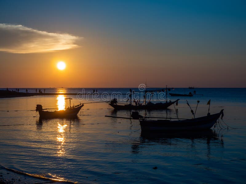 Silhouette d'un bateau de pêche dans les rayons du coucher de soleil avec des nuages images stock Silhouette d'un bateau de pêche dans les rayons du coucher de soleil avec des nuages images stock