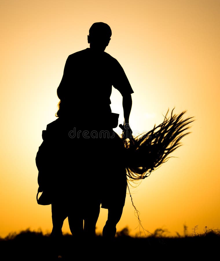 Silhouette d'un homme sur un cheval au coucher du soleil photographie stock libre de droits Silhouette d'un homme sur un cheval au coucher du soleil photographie stock libre de droits