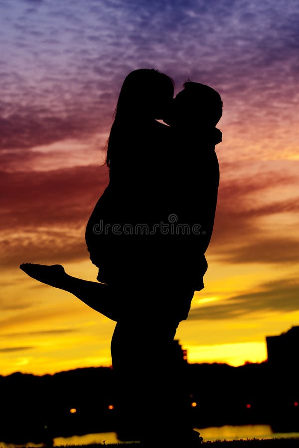 Silhouette d'un jeune couple par l'eau photographie stock libre de droits Silhouette d'un jeune couple par l'eau photographie stock libre de droits