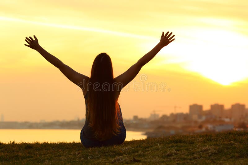 Silhouette d'une femme célébrant au coucher du soleil en banlieue photos stock