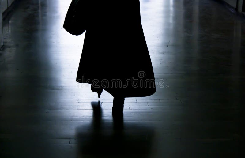 Silhouette d'une femme marchant loin dans l'allée foncée
