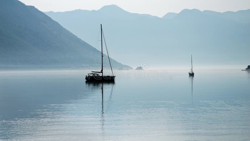 Silhouette de deux yachts amarrés dans un port de mer calme avec brouillard matinal et brouillard