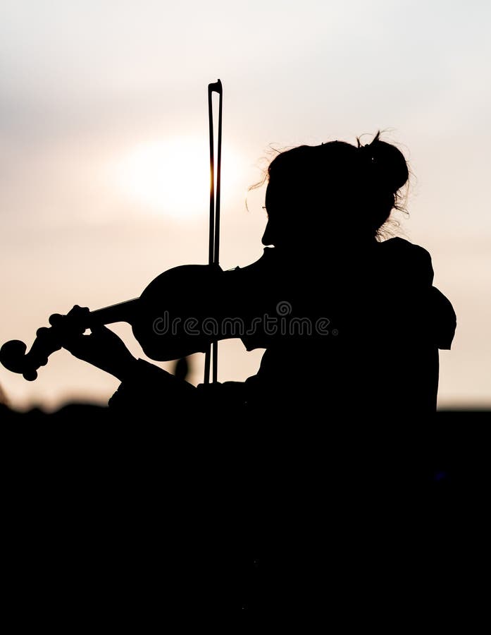 Silhouette de femelle jouant le violon pendant le coucher du soleil contre le soleil - Prague rentré image stock Silhouette de femelle jouant le violon pendant le coucher du soleil contre le soleil - Prague rentré image stock