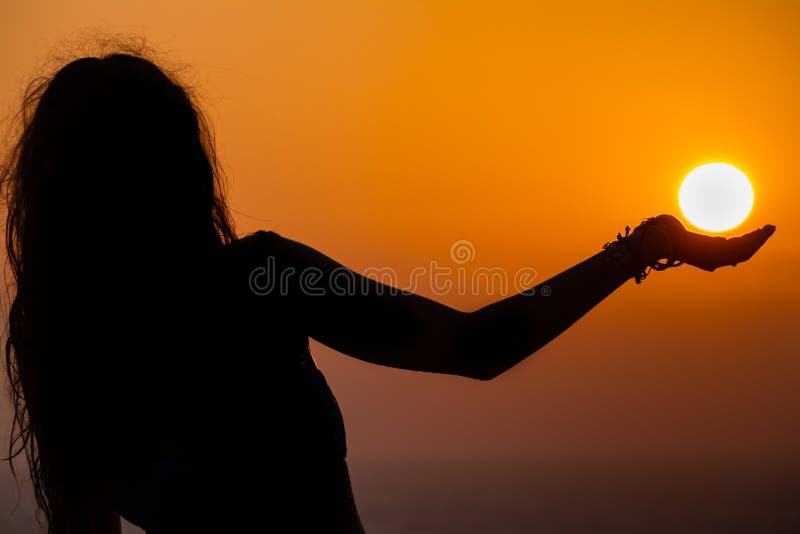 Silhouette de fille, sa paume semblant soutenir le soleil As photo stock Silhouette de fille, sa paume semblant soutenir le soleil As photo stock