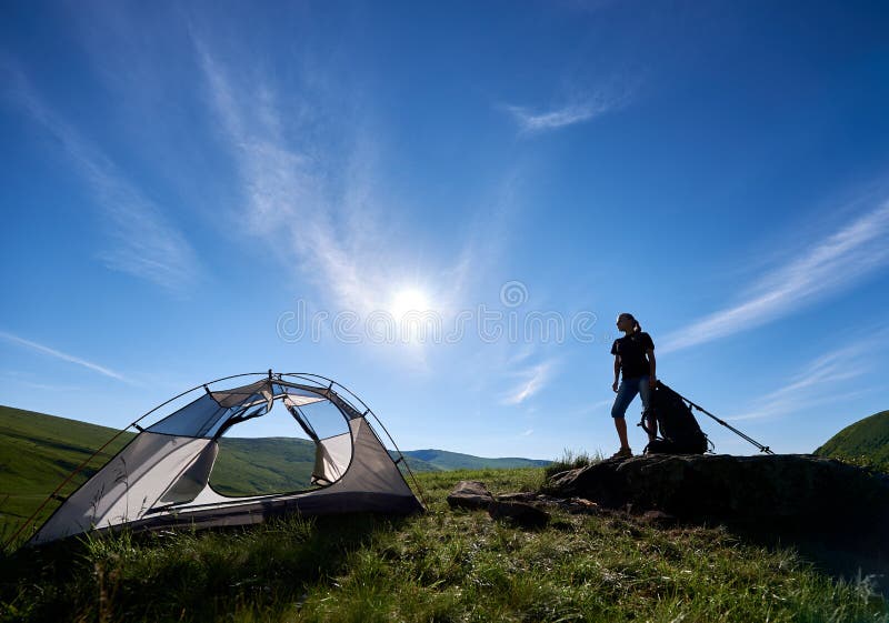 Silhouette de grimpeuse de femme près du camping contre le ciel bleu pendant le matin photo stock Silhouette de grimpeuse de femme près du camping contre le ciel bleu pendant le matin photo stock