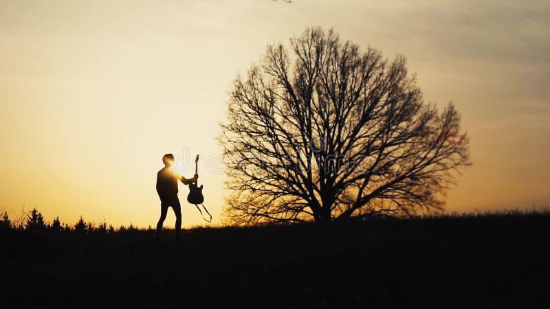 Silhouette de guitariste au mouvement lent de coucher du soleil