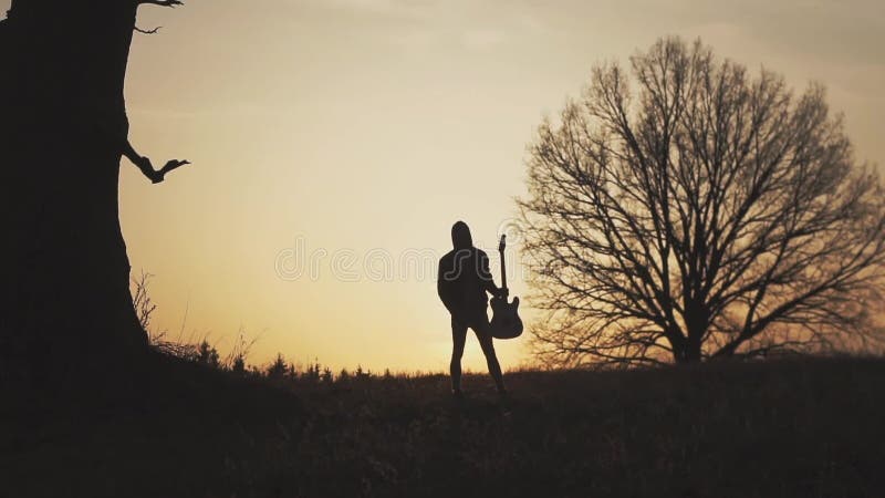 Silhouette de guitariste au mouvement lent de coucher du soleil