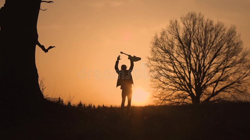 Silhouette de guitariste au mouvement lent de coucher du soleil Le guitariste ondule sa main