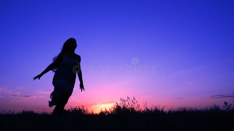 Silhouette de jeune fille fonctionnant contre le ciel rose