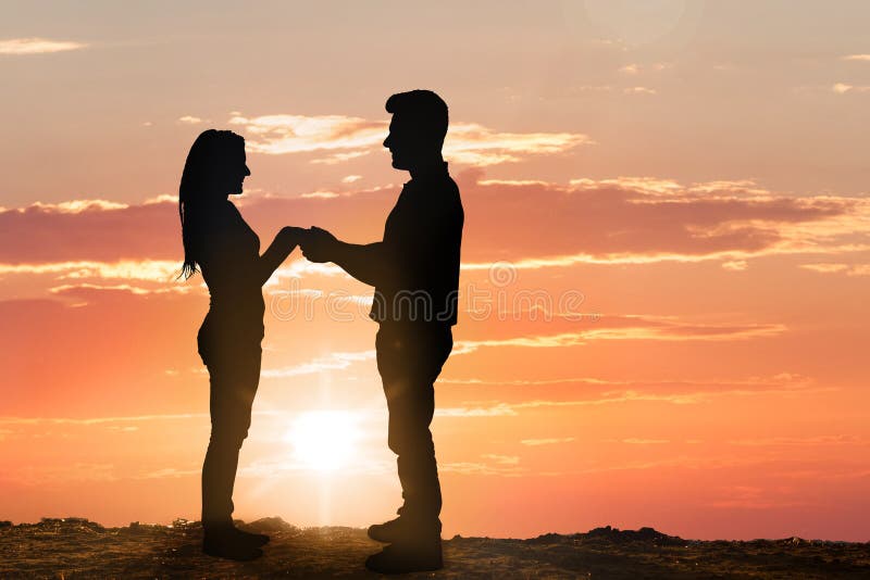 Silhouette de jeunes couples au coucher du soleil photo stock Silhouette de jeunes couples au coucher du soleil photo stock