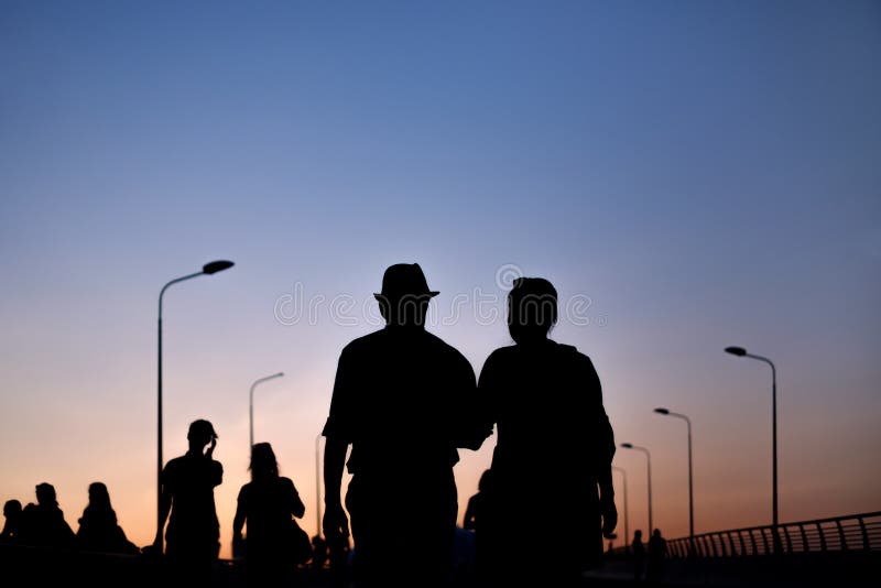 Silhouette de l'homme et de la femme de couples marchant sur le coucher du soleil photo stock Silhouette de l'homme et de la femme de couples marchant sur le coucher du soleil photo stock