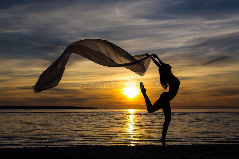 Silhouette de la danse sexy mince de fille avec l'écharpe sur la plage images libres de droits Silhouette de la danse sexy mince de fille avec l'écharpe sur la plage images libres de droits