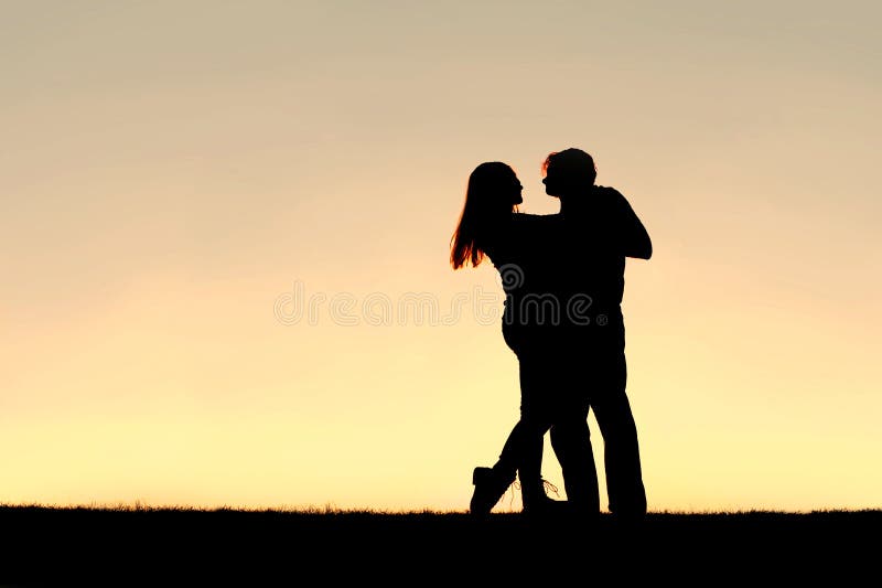 Silhouette de la jeune danse heureuse de couples au coucher du soleil images stock Silhouette de la jeune danse heureuse de couples au coucher du soleil images stock