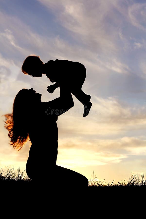 Silhouette de mère heureuse jouant dehors avec le bébé photographie stock libre de droits
