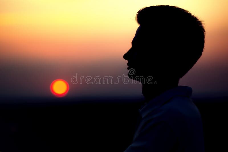 Silhouette de rofile d'un visage du ` s de jeune homme au coucher du soleil dans un domaine image stock Silhouette de rofile d'un visage du ` s de jeune homme au coucher du soleil dans un domaine image stock