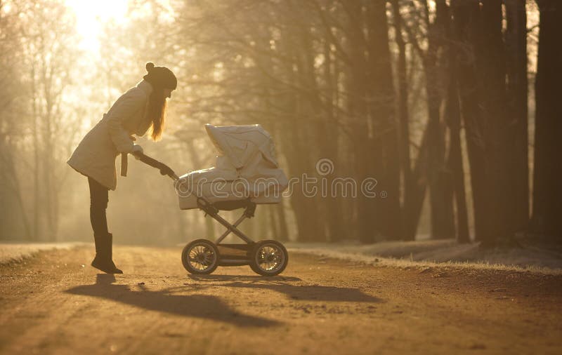 Silhouette der jungen Frau bei sonnigem Fußweg und Sichtweise des Kindes im Kinderwagen Sonniger Winterpark, -kinderbetreuung und