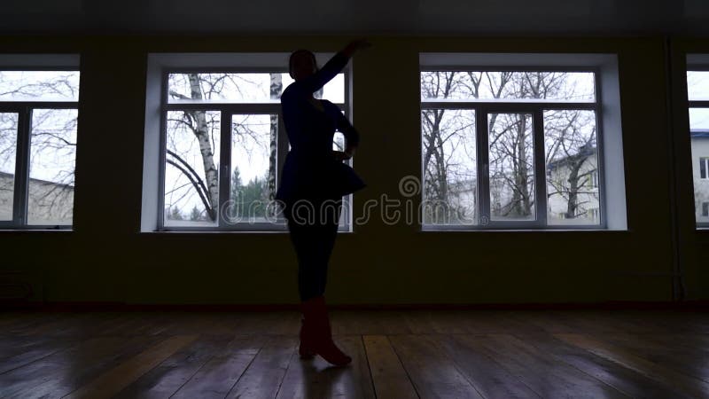 Silhouette di una ballerina che si allena in un'aula buia