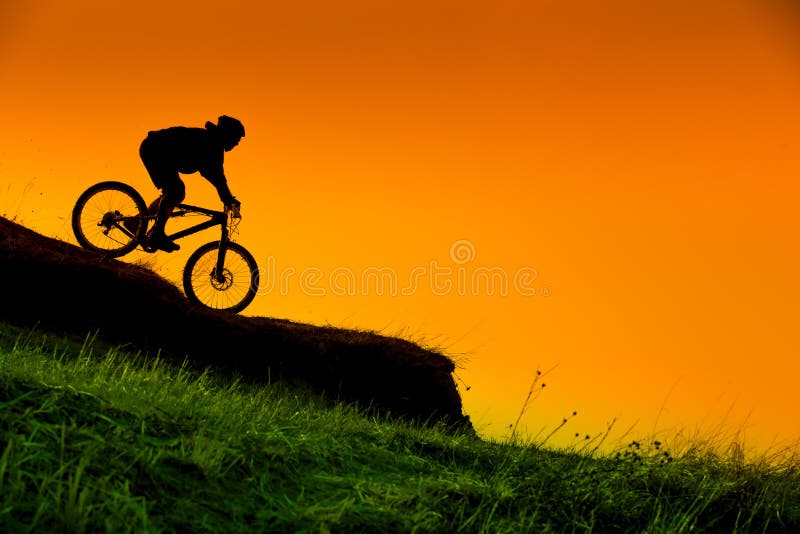 Silhouette of downhill mountain bike rider at sunset