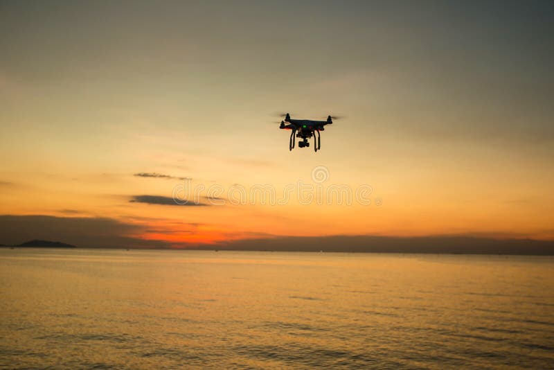 Silhouette drone against the background of the sunset. Flying drones in the evening sky. UAV Drone with digital camera. stock photos