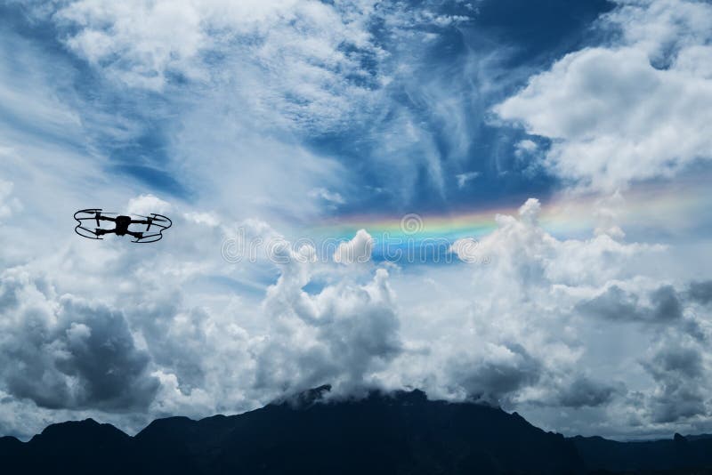 Silhouette drone flying on blue sky with rainbow royalty free stock photo