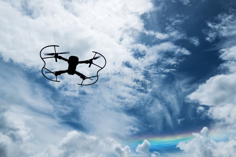Silhouette drone flying on blue sky with rainbow stock photography