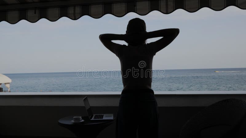 Silhouette einer Frau auf dem Balkon mit Meerblick.