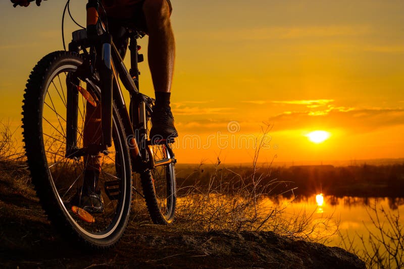 Silhouette of Enduro Cyclist Riding the Mountain Bike on the Rocky Trail at Sunset. Active Lifestyle Concept. Space for Text.