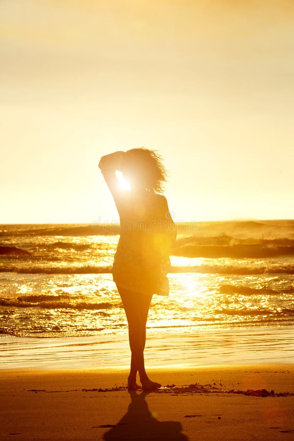 Silhouette of fashion model walking on beach during sunset